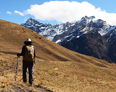 Woman walking on Andean roads above the mountains and near snow-capped mountains