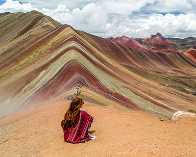 Woman in an Andean poncho with panoramic view of Rainbow Mountain