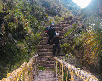Men descending steps to reach Huchuy Qosqo in the middle of an Andean forest