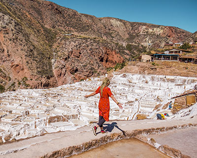 Woman walking with open arms in the middle of the Maras salt flat
