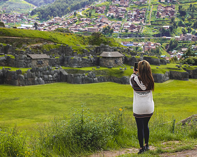 Woman is taking a photograph of Saqsayhuaman