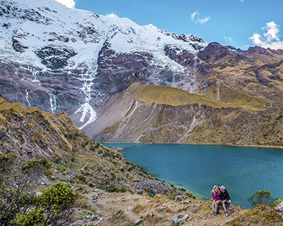 Couple of travelers looking at the Humantay Lake and the snow-capped mountain