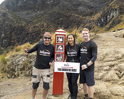A couple and their guide passing one of the landmarks on the Inca Trail